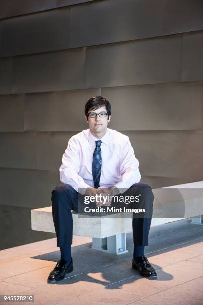 hispanic business man in an office lobby. - piernas separadas fotografías e imágenes de stock