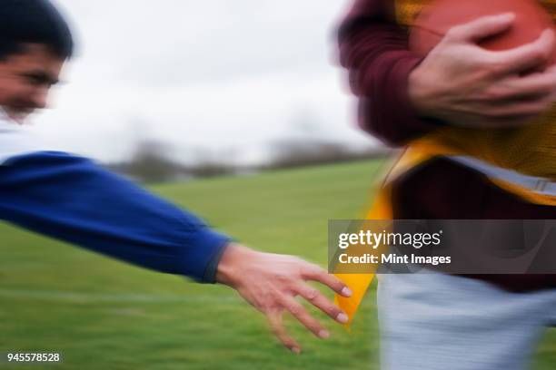 close up of a sports player reaching for a flag to score a point in non-contact flag american football game. - kinder football stock-fotos und bilder