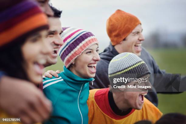 group of men and women friends cheering at an informal sporting event in winter. - sports team spirit stock pictures, royalty-free photos & images