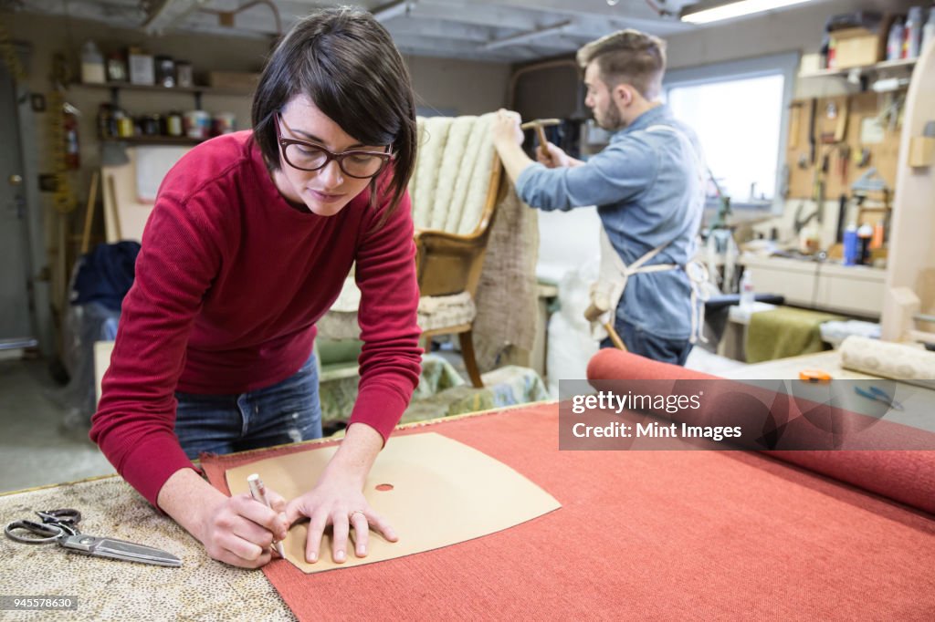 A young Caucasian couple working on a chair as a team of upholsterers.
