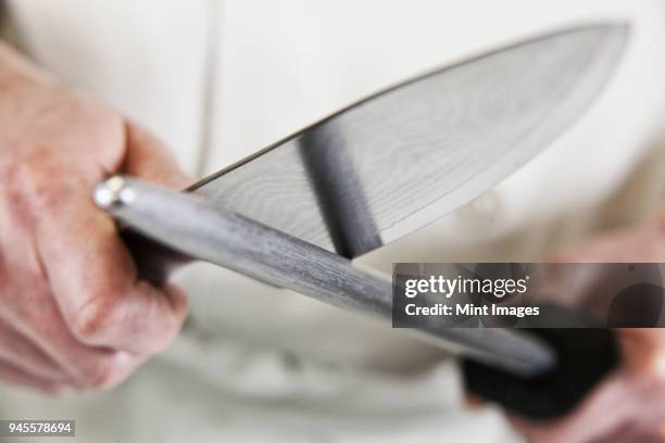 close-up of a chef sharpening a large kitchen knife blade with a steel. - kitchen knife bildbanksfoton och bilder