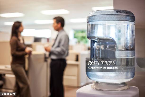 caucasian man and woman executives in cubicle area of new office space - water cooler stock pictures, royalty-free photos & images