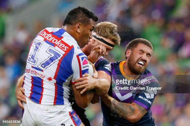 Jacob Saifiti of the Knights is tackled by Christian Welch and Kenny Bromwich of the Storm during the round six NRL match between the Melbourne Storm...