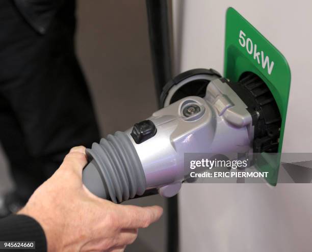 Man shows how tyo use a Schneider Electric recharging spot for electric cars at the Paris Auto Show on the first day of the two-day press days on...