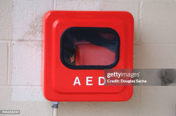 automated external defibrillator (aed) for heart attack emergency is mounted on a wall in a red box - defibrillator stock pictures, royalty-free photos & images