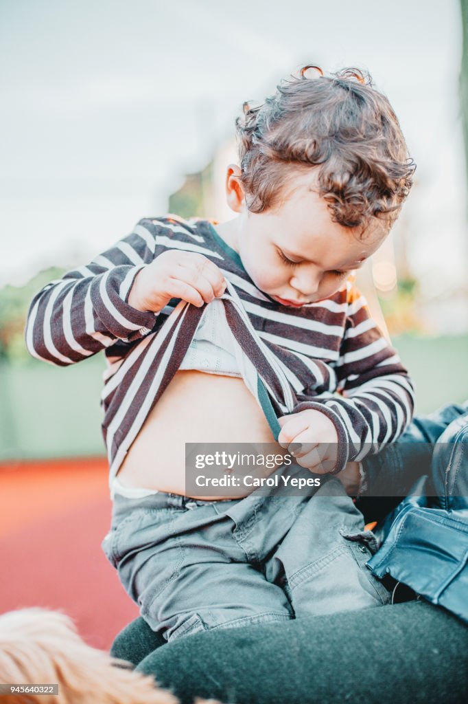 Little boy looking at his belly button outdoors