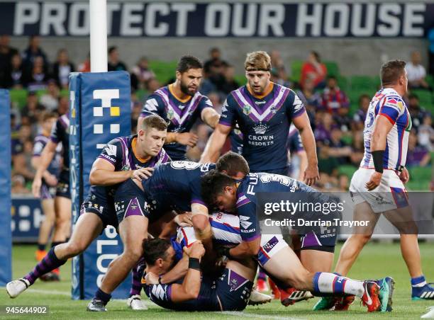 Storm players hold up Jamie Buhrer of the Knights to prevent a try during the round six NRL match between the Melbourne Storm and the Newcastle...
