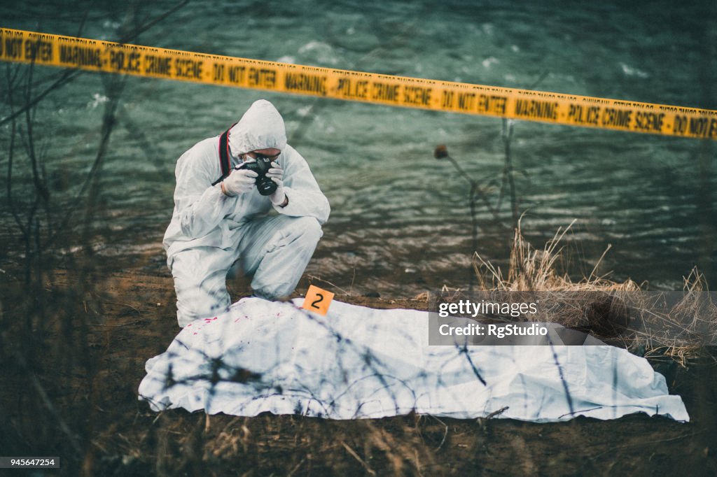 Photographer taking photos of crime scene by the river