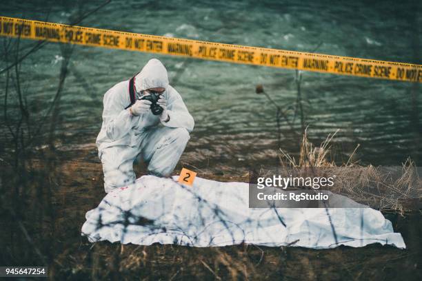 photographer taking photos of crime scene by the river - killing imagens e fotografias de stock