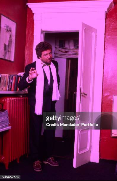 The comedian Beppe Grillo joking on the doorway in elegant clothes. 1985