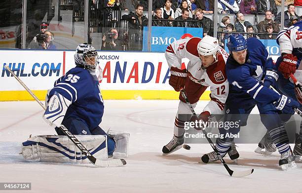 Ian White of the Toronto Maple Leafs battles with Paul Bissonnette of the Phoenix Coyotes in front of goalie Vesa Toskala during game action December...