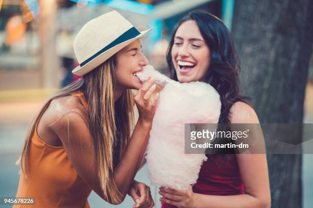happy women eating pink cotton candy - cotton candy stock pictures, royalty-free photos & images