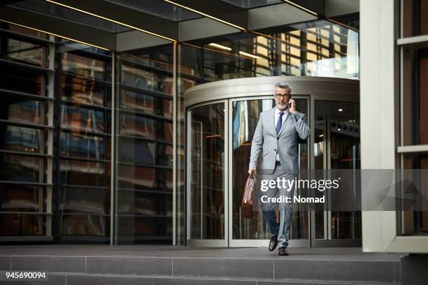 businessman using smartphone while leaving office - leaving building stock pictures, royalty-free photos & images