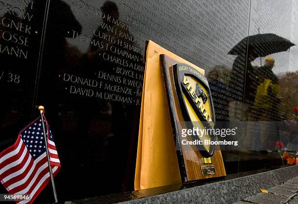 An American flag and a military plaque are some of the items left by visitors sit at along the wall of the Vietnam Memorial in Washington, D.C.,...