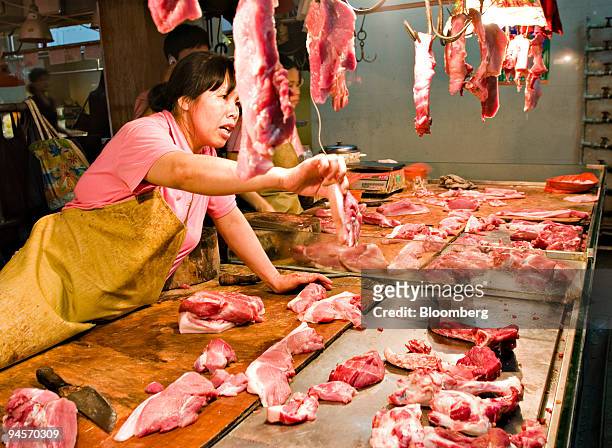 Vendor selling pork and other cuts of meat drums up business at a market in Guangzhou, China, on Monday, June 11, 2007. China, the world's biggest...