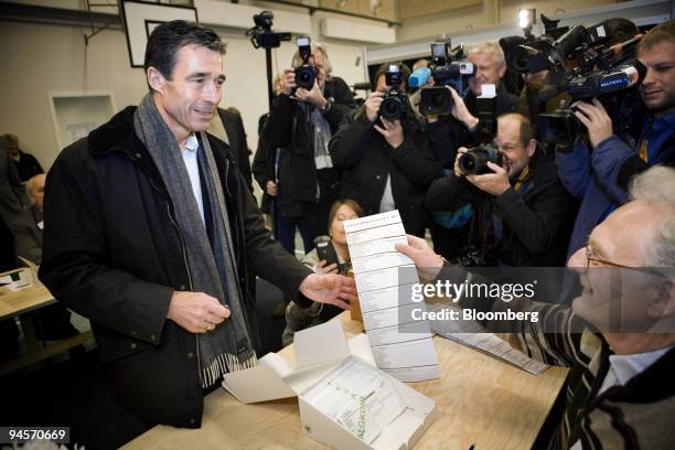 Anders Fogh Rasmussen, the Danish prime minister and leader of the Liberal Party, left, collects his voting slip at the polling station in Naerum,...