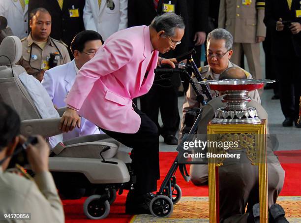 Bhumibol Adulyadej, the King of Thailand, helps himself out of a wheelchair and onto a walker after leaving a hospital in Bangkok, Thailand, on...