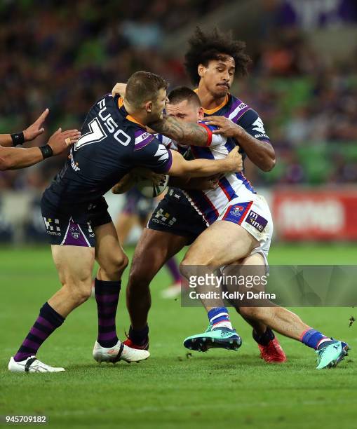 Shaun Kenny-Dowall of the Knights is tackled by Ryley Jacks and Felise Kaufusi of the Storm during the round six NRL match between the Melbourne...
