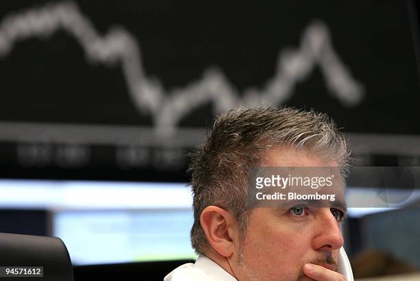 Trader Dirk Mueller works as the DAX index curve is displayed on a screen behind him, at the Deutsche Boerse AG, in Frankfurt, Germany, on Wednesday,...