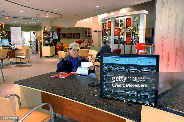 Customer David Perez sits at one of the contemporary sales desks in the newly designed showroom at the Saturn of Danbury dealership in Danbury,...