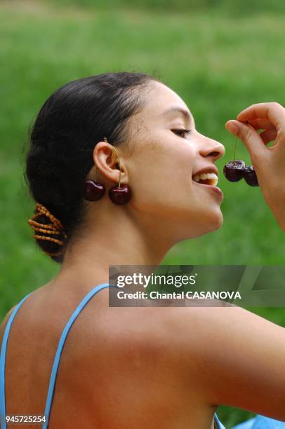 Femme avec des cerises aux oreilles.