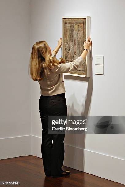 Jessie Fertig, a specialist at Christie's, hangs the painting, "Atelier I" by Aberto Giaocmetti during a preview exhibition at Christie's in New...