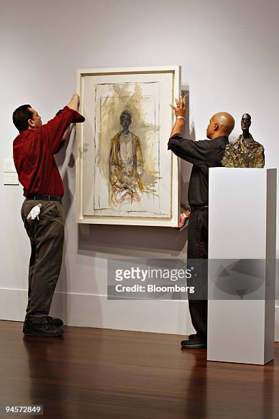 Andrew Bogats, left, and Rick Small, hang the painting, "Annette au manteau" by Alberto Giacometti during a preview exhibition at Christie's in New...