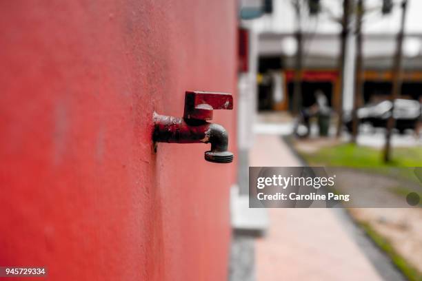 red wall with a faucet. - caroline pang stockfoto's en -beelden