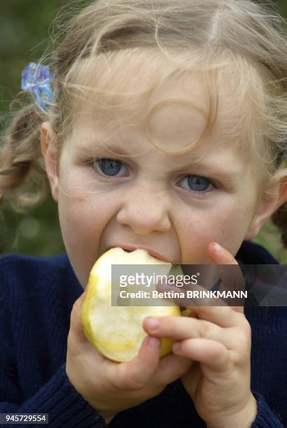 Une fille de 4 ans croque dans une pomme.