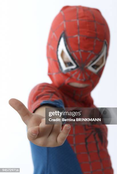 Un enfant deguise en spiderman tend le bras et fait le geste comme s'il allait lancer la toile d'araignee du superhero.