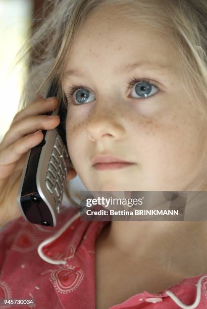 Un enfant de 6 ans ecoute quelqu'un qui lui parle au telephone.