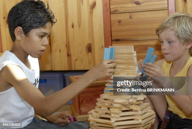 Deux gar?ons jouent a construire une boule en Kapla.