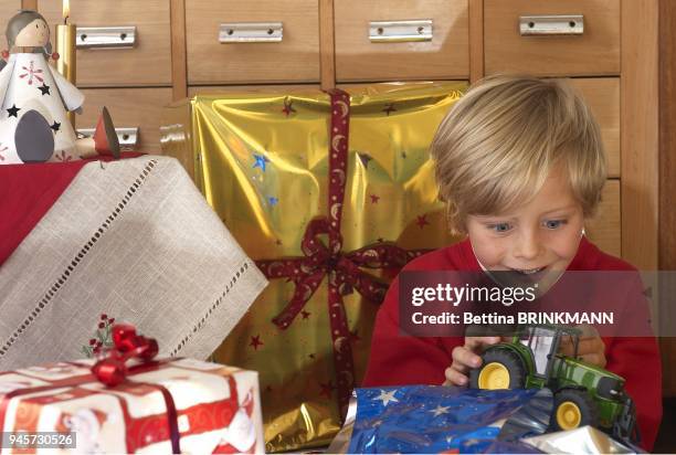 Un petit garcon de 6 ans deballe un tracteur comme cadeau de Noel et est tout content.