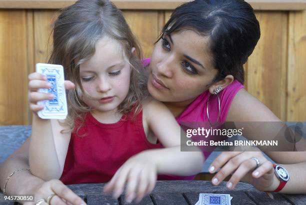 Une adolescente joue aux cartes avec une fille de 5 ans.