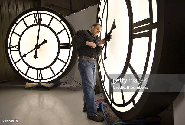 Peter Sugnie, an employee of Electric Time, adjusts the hands of a 96-inch clock at the factory in Medfield, Massachusetts, U.S., on Monday, October...