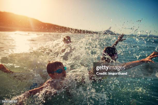niños super divertido salpicaduras y saltando en las olas del mar - niño bañandose fotografías e imágenes de stock