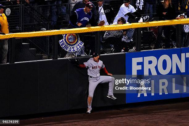 Jacoby Ellsbury of the Boston Red Sox crashes into the left field wall as he catches a ball hit by Jamey Carroll of the Colorado Rockies in Game 4 of...