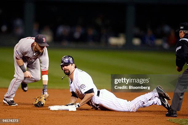 Todd Helton of the Colorado Rockies, center, slides in under the tag of Dustin Pedroia of the Boston Red Sox after hitting a double during Game 4 of...