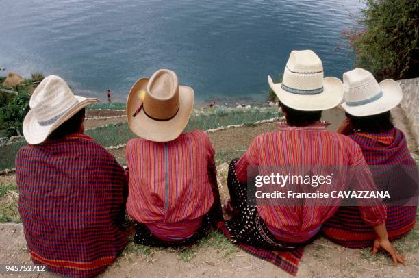 JEUNES HOMMES INDIENS MAYAS SE REPOSANT FACE AU LAC ATITLAN, SAN ANTONIO PALOPO, GUATEMALA.