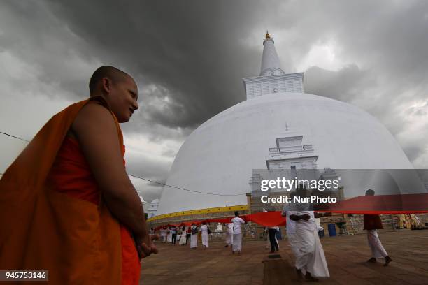 Buddhist monk looks on as Sri Lankan Buddhist devotees perform religious rites on the eve of Sinhala and Tamil New Year at Ruwanweliseya Stupa ,...