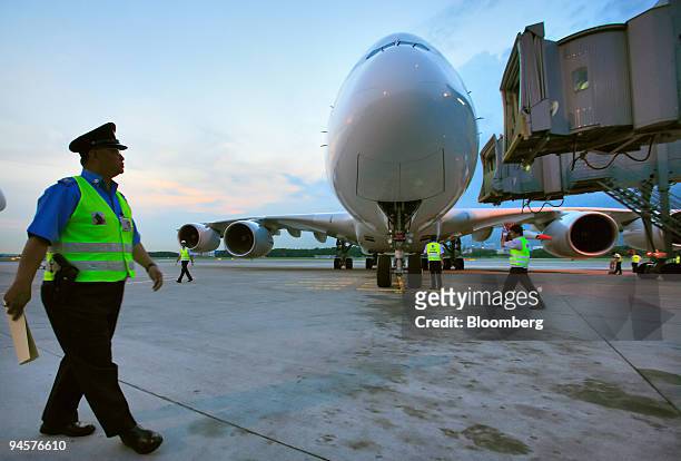 Policeman patrols in front of Singapore Airlines Ltd.'s first Airbus A380 superjumbo passenger plane as is sits parked at the air bridge at Changi...