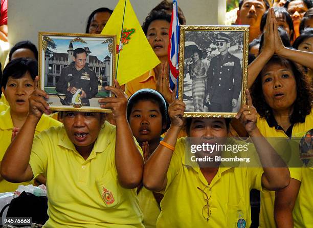 Wellwishers of Thai King Bhumibol Adulyadej hold up pictures as his wife, Queen Sirikit, unseen, arrives at the Siriraj Hospital in Bangkok,...