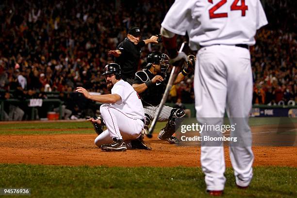 Kevin Youkilis of the Boston Red Sox, left, slides safely into home past the tag of Yorvit Torrealba of the Colorado Rockies during Game 1 of the...