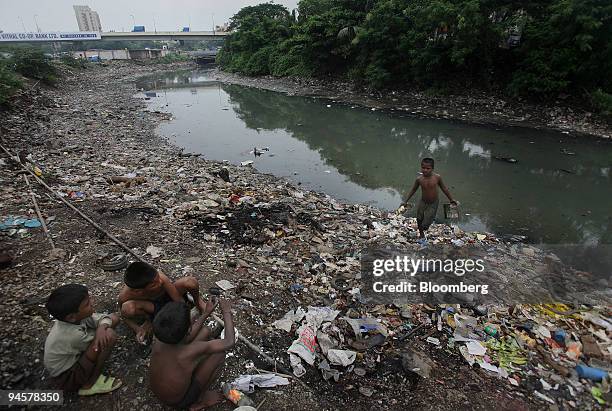 Children collect scraps and rags from the garbage strewn banks of an open water source in Mumbai, India, on Wednesday, Sept. 19, 2007. Heads of state...