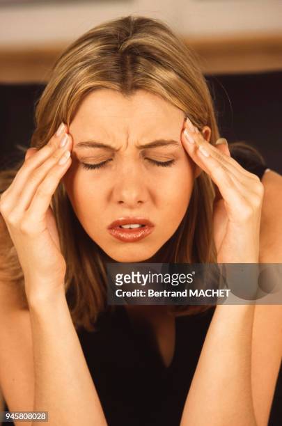 Femme atteinte d'une migraine prenant un cachet d'aspirine.