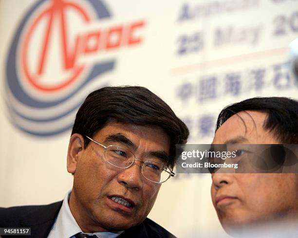 Fu Chengyu, chairman and chief executive officer of Cnooc Ltd., speaks to Zhou Shouwei, president and executive director of Cnooc. Ltd., during a...