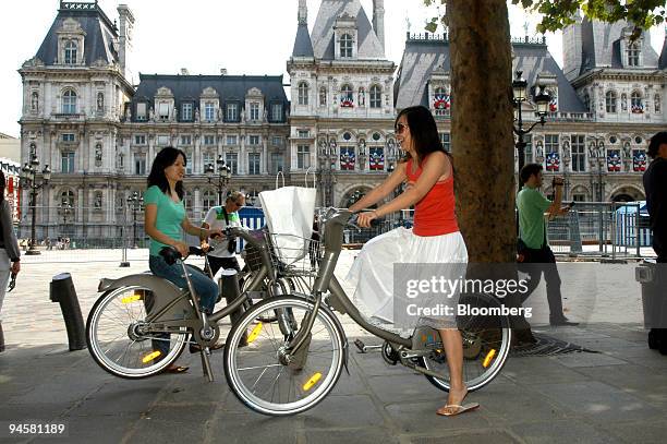 Two tourists hire bicycles in front of City Hall on launch day of the Velib bicycle-sharing scheme in Paris, France, on Sunday, July 15, 2007. The 90...