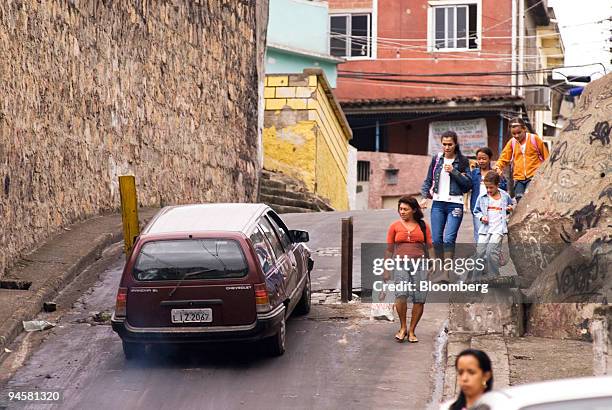 Pedestrians and a car pass by a blockade in an alley off Itararee Avenue at the Complexo do Alemao in the Favela de Grota in Rio de Janeiro, Brazil,...