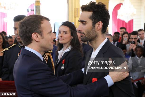 French President Emmanuel Macron congratulates France's five-time Olympic champion Martin Fourcade after he was awarded Officier of the Legion of...
