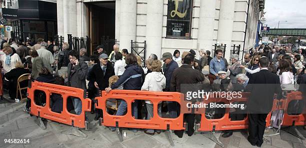 Northern Rock customers queue from the banks entrance,left, onto the pavement outside the branch in Golders Green, London, U.K., on Monday, Sept. 17,...
